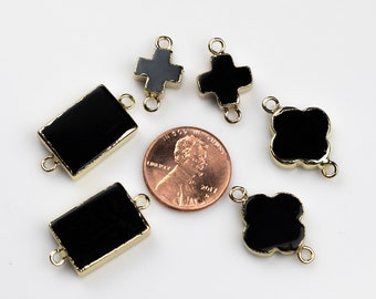 May include: Assortment of black gemstone connector charms with gold-toned accents. The charms are in the shapes of a rectangle, cross, and four-leaf clover. A penny is included for size reference.