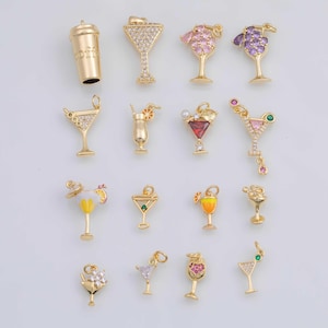 May include: A collection of gold-colored cocktail charms with various designs, including martini glasses, a coffee cup, and other drink-themed pendants. Some charms are adorned with clear and colored gemstones.