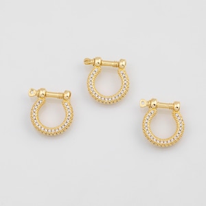 May include: Three gold-colored, U-shaped jewelry clasps with a row of small, clear stones around the curve. Each clasp has a small bar with a loop on one end and a screw-like closure on the other.