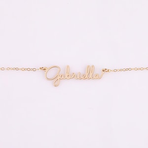 May include: A gold necklace with the name "Gabriella" written in cursive script.