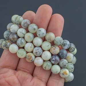 May include: A strand of green, white, and brown agate beads. The beads are round and have a natural, polished finish.