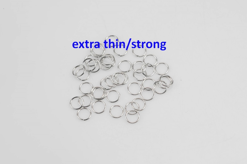 May include: A pile of silver jump rings, labeled "extra thin/strong". These rings are small and perfect for jewelry making.