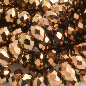 May include: A strand of faceted, copper-colored glass beads. The beads are small and have a shiny, metallic finish.