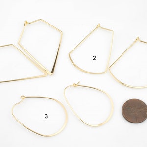May include: Five pairs of gold hoop earrings in different geometric shapes. The earrings are arranged on a white surface with a penny for scale.