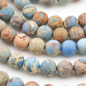 May include: A strand of blue, brown, and beige jasper beads. The beads are round and have a marbled pattern.