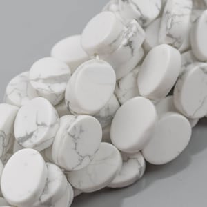 May include: A strand of white howlite beads, each bead is oval shaped and has a smooth, polished finish. The beads have a natural marbling pattern with white and gray tones.