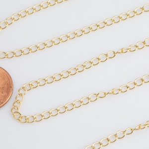 May include: Gold chain necklace with a classic cable link design. The chain is shown next to a US penny for scale.