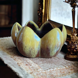 以下が含まれることがあります： ユニークな花びらのようなデザインのセラミックボウル。ボウルは、黄色と茶色の色合いの光沢のある仕上がりで、温かみのある美しさを生み出しています。内側はより暗い赤茶色の色合いです。インテリアデコレーションに最適です。