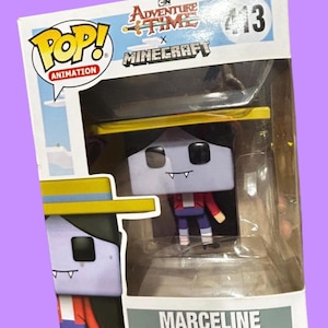 Puede incluir: Figura de vinilo Funko Pop! de Marceline de Adventure Time x Minecraft, en una vitrina transparente. Marceline tiene una cabeza cuadrada, pelo negro y una chaqueta roja. La caja muestra los logotipos de Adventure Time y Minecraft.