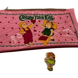 May include: Pink vinyl Cabbage Patch Kids pencil case with a heart pattern and two Cabbage Patch Kids characters. The case has a zipper closure and the text "Cabbage Patch Kids" printed on the front.