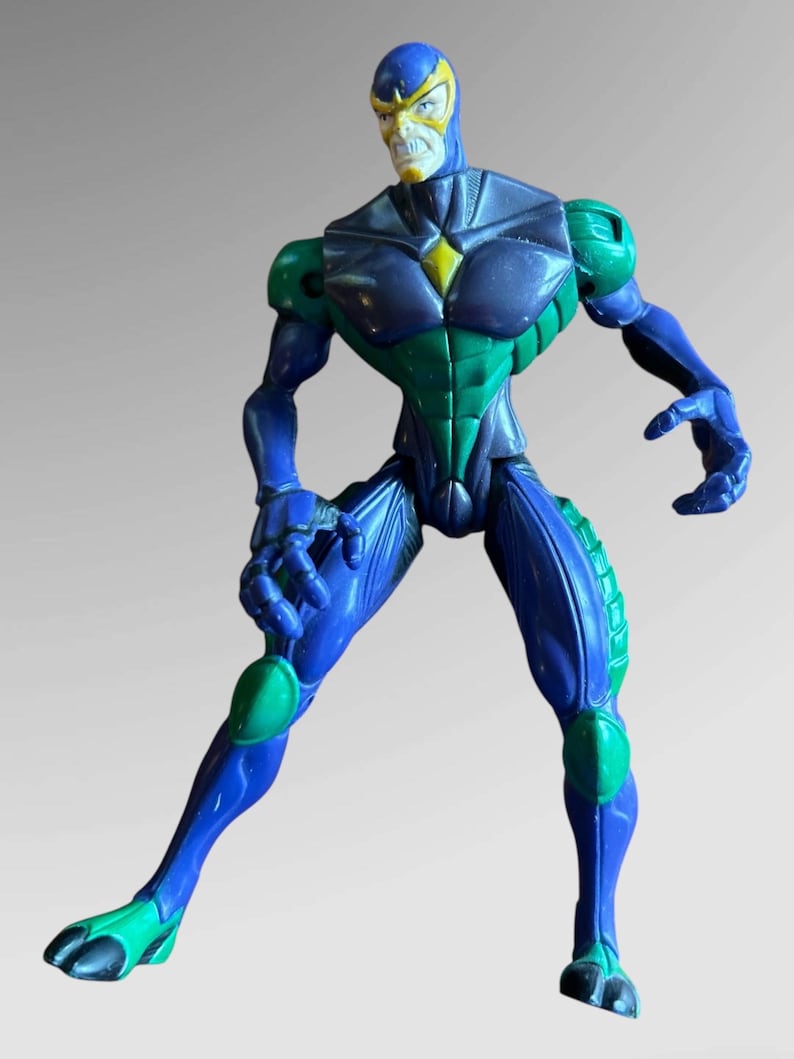 May include: A blue and green action figure with a yellow and white mask. The figure is in a fighting pose with its arms raised.