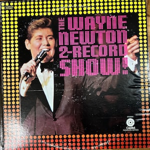 以下が含まれることがあります： 黒のスーツと白いシャツを着てマイクを持ったウェイン・ニュートンの写真が載っている、ビンテージのビニールレコードアルバムのジャケット。アルバムのタイトルは「The Wayne Newton 2-Record Show!」で、黒の背景にピンクの文字で書かれている。アルバムのジャケットは黄色と赤のドット柄である。