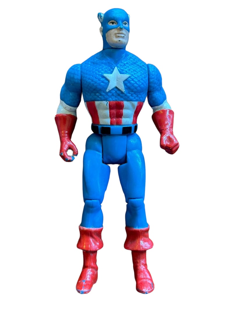Puede incluir: Una figura de acci&oacute;n vintage de Capit&aacute;n Am&eacute;rica, con su ic&oacute;nico traje rojo, blanco y azul. La figura tiene un cuerpo azul, botas rojas y una estrella blanca en el pecho.