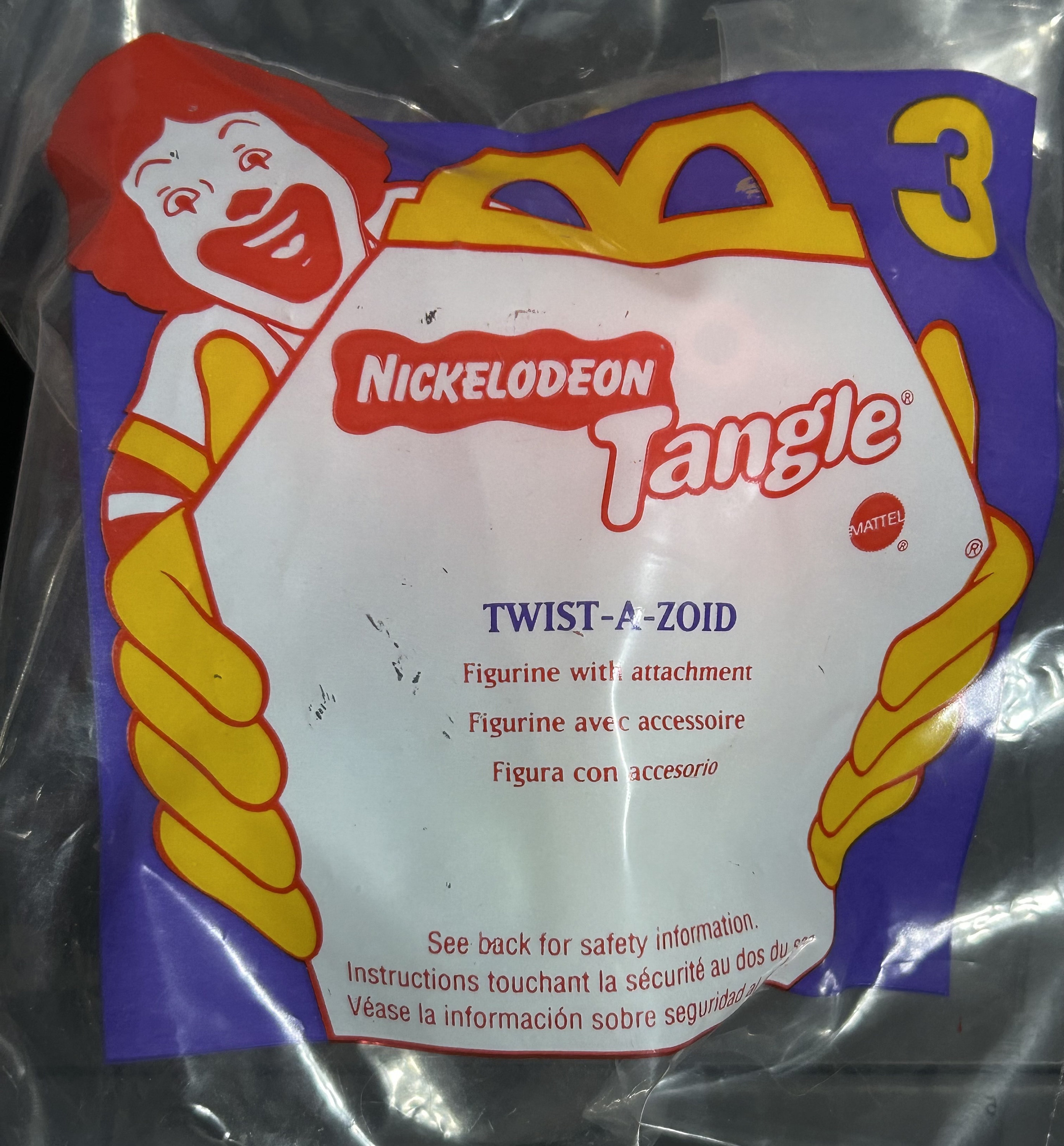 May include: A sealed plastic bag featuring a Nickelodeon Tangle Twist-A-Zoid figurine. The bag has a purple and yellow design with the McDonald's clown mascot. Text includes "Figurine with attachment" and "MATTEL".