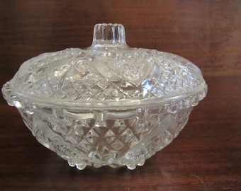 May include: A clear glass candy dish with a lid. The dish and lid are both decorated with a diamond pattern and floral motifs.