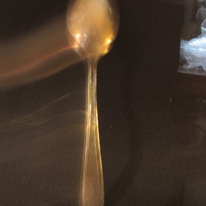 May include: A silver spoon with a rounded bowl and a long, slender handle.