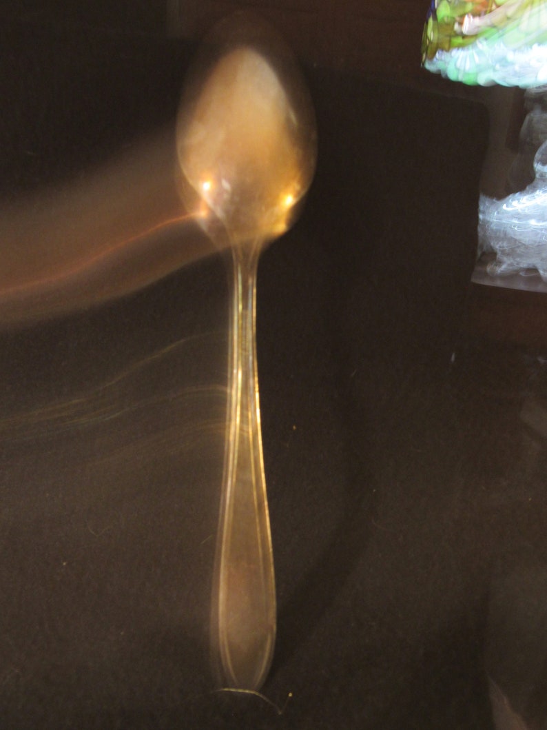 May include: A silver spoon with a rounded bowl and a long, slender handle.