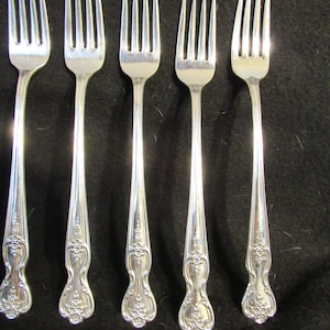 Puede incluir: Juego de seis tenedores de plata con mangos ornamentados. Los tenedores tienen un diseño tradicional con un mango redondeado y un patrón floral decorativo.