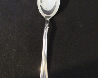 May include: A silver spoon with a rounded bowl and a long, curved handle.