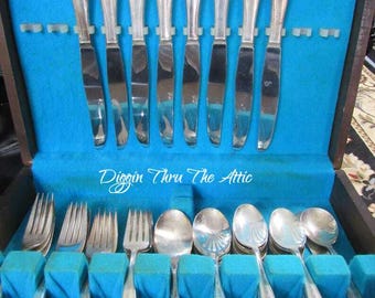 May include: A wooden box with a blue velvet lining contains a set of silverware. The silverware includes knives, forks, and spoons. The silverware is in a vintage style with ornate handles.