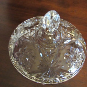 May include: Clear glass lid with a starburst pattern and a knob on top.