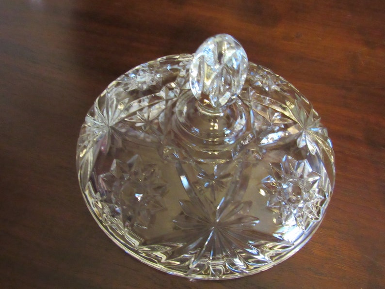 May include: Clear glass lid with a starburst pattern and a knob on top.