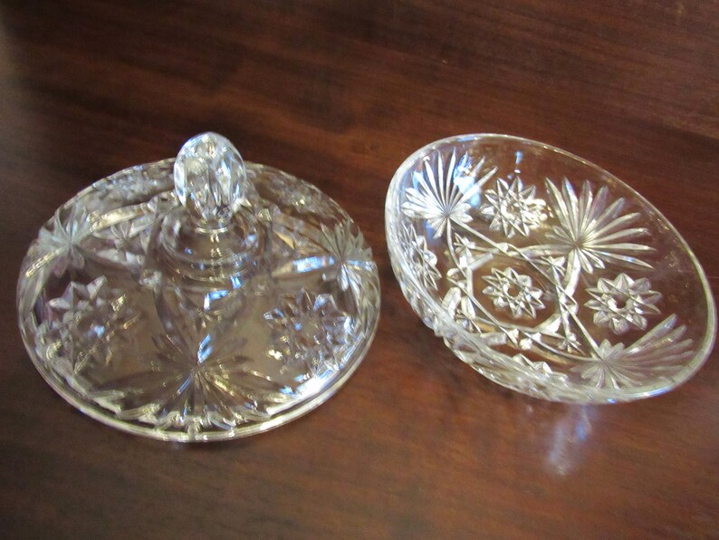 May include: A clear glass bowl with a lid, both with a cut-glass star pattern. The lid has a knob on top.