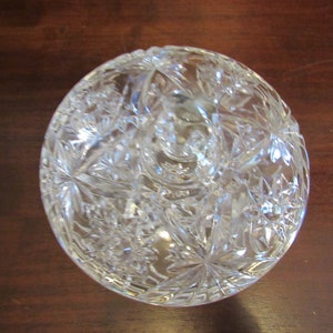 May include: A clear glass bowl with a cut glass design. The bowl is round and has a raised center.