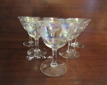 May include: Set of six clear glass cocktail glasses with an iridescent finish and etched floral designs. The glasses have a stemmed base and a wide, shallow bowl.