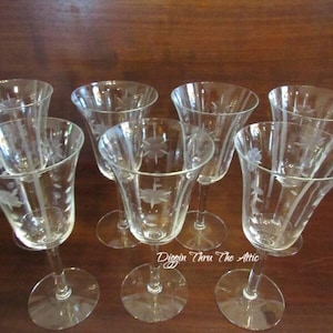 May include: Set of six clear glass wine glasses with etched floral designs. The glasses have a tall, slender stem and a wide bowl.