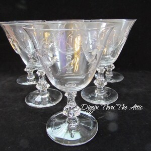 May include: Set of six clear glass wine glasses with etched floral designs. The glasses have a stemmed base and a wide bowl.