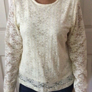 May include: A white lace long-sleeve shirt with a round neckline.