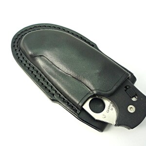 May include: A black leather knife sheath with a silver pocket knife inside. The knife has a black handle and a silver blade with the text "Golden" on it.