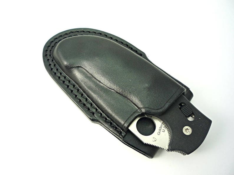 May include: A black leather knife sheath with a silver pocket knife inside. The knife has a black handle and a silver blade with the text "Golden" on it.