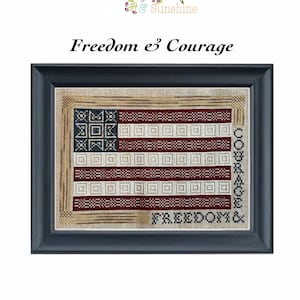 Op de afbeelding: Een kruissteek borduurontwerp met een Amerikaanse vlag met de woorden "Freedom & Courage" geborduurd in rode en blauwe draad. Het ontwerp is ingelijst in een zwart frame.