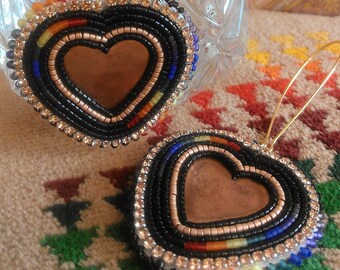 May include: A pair of beaded heart earrings with a copper center. The earrings are black with rainbow colored accents and clear rhinestones.
