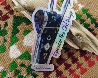 May include: A holographic sticker with a beaded Native American design and the text "Remember the Old Ways". The sticker is on a piece of driftwood.