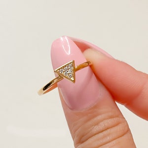 May include: A gold ring with a triangle-shaped stone set with small clear stones.