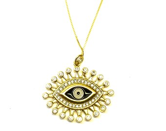 May include: A gold necklace with a large evil eye pendant. The pendant is surrounded by small clear stones and has a black and white eye design.