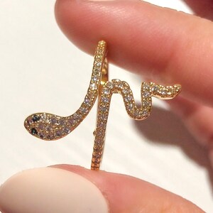 May include: A gold snake ring with clear and black stones. The snake is coiled around the ring band.