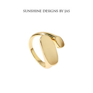 May include: A gold-toned ring with a unique design featuring a curved band and a large oval-shaped piece. The ring is a statement piece and would add a touch of modern elegance to any outfit.