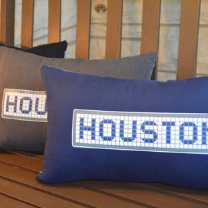 May include: Three decorative pillows with the word "HOUSTON" spelled out in a mosaic tile pattern. The pillows are navy blue, gray, and black.