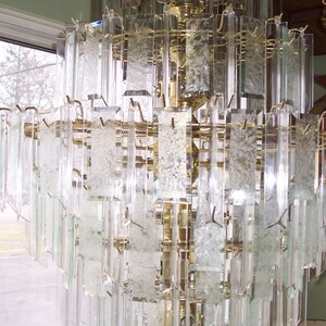 May include: A large, multi-tiered chandelier with clear glass prisms. The chandelier is made of brass and has a traditional design.