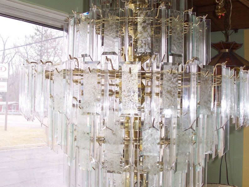 May include: A large, multi-tiered chandelier with clear glass prisms. The chandelier is made of brass and has a traditional design.