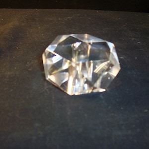 May include: A clear glass paperweight shaped like a diamond with many facets.