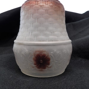 Może przedstawiać: Biały szklany klosz lampy z brązowym wzorem tkanym i brązowym wzorem kwiatowym. Klosz ma zaokrąglone dno i lekko rozszerzoną górę.