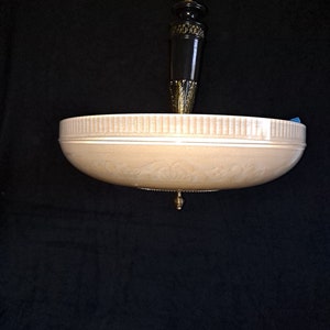 May include: A beige ceiling light fixture with a decorative gold trim and a black and gold pendant.