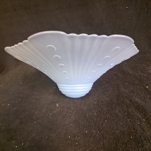 May include: A light blue, fan-shaped glass lampshade with a scalloped edge and a series of small, circular indentations. The shade has a ribbed design and a rounded base. The lampshade is likely for a ceiling fixture or table lamp.