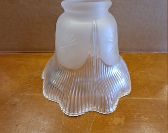 May include: A frosted glass lampshade with a scalloped edge and a starburst pattern. The shade is clear and has a ribbed texture.
