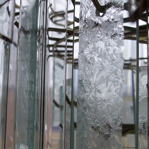 May include: Close-up of a crystal chandelier with multiple clear glass prisms hanging from a metal frame.